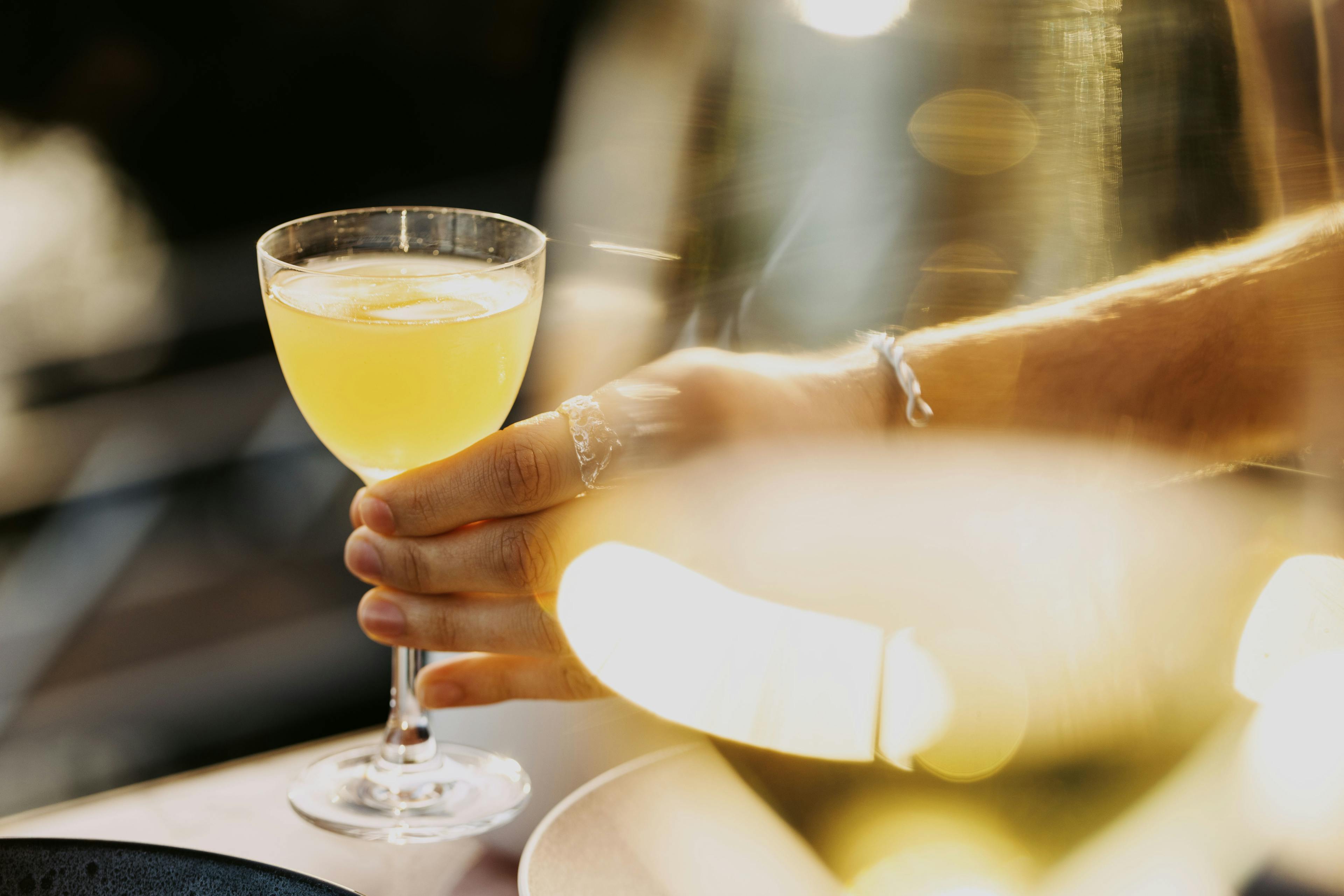 A hand reaches for a crafted beverage in a glass