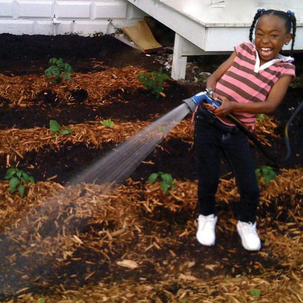 A child excitedly watering a garden