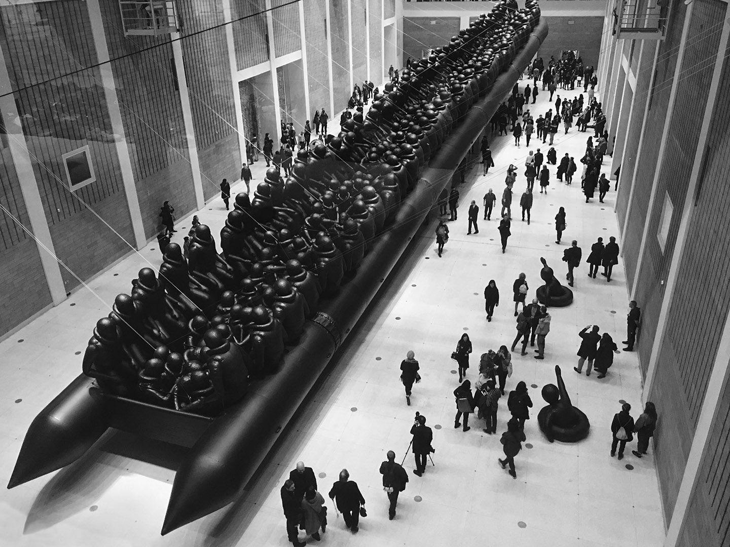 A black and white image of a vast black inflatable boat filled with figures of soldiers